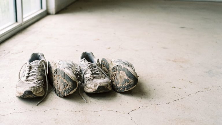 Zapatillas de correr usadas alineadas en el suelo mostrando el desgaste de la suela