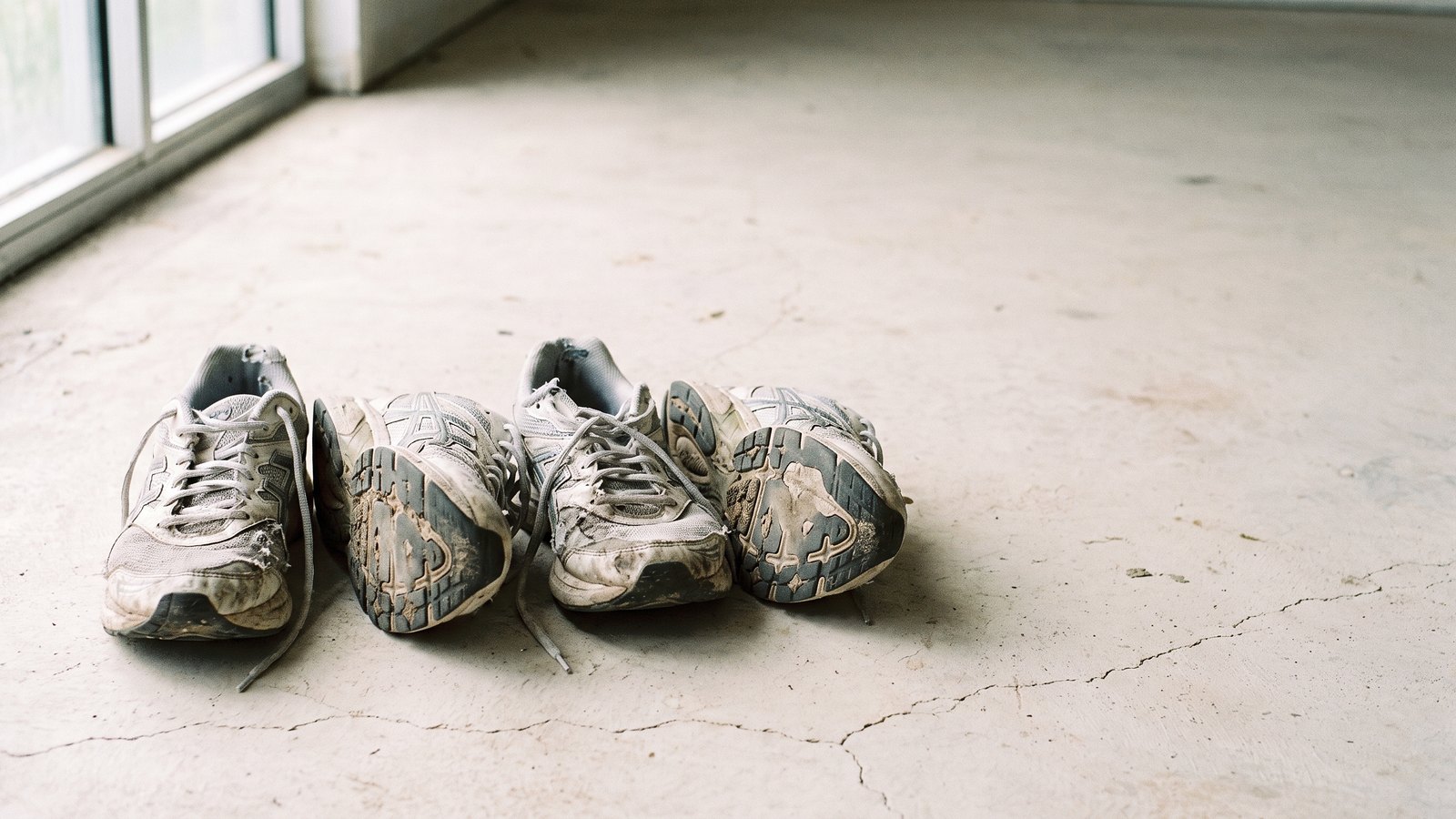 Zapatillas de correr usadas alineadas en el suelo mostrando el desgaste de la suela