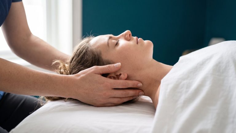 Manos de osteópata sosteniendo con suavidad la cabeza y el cuello de una paciente tumbada
