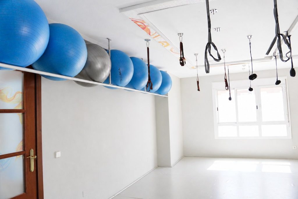 Sala de pilates terapéutico de la Clínica Saavedra en Roquetas de Mar con fitballs y arneses de suspensión