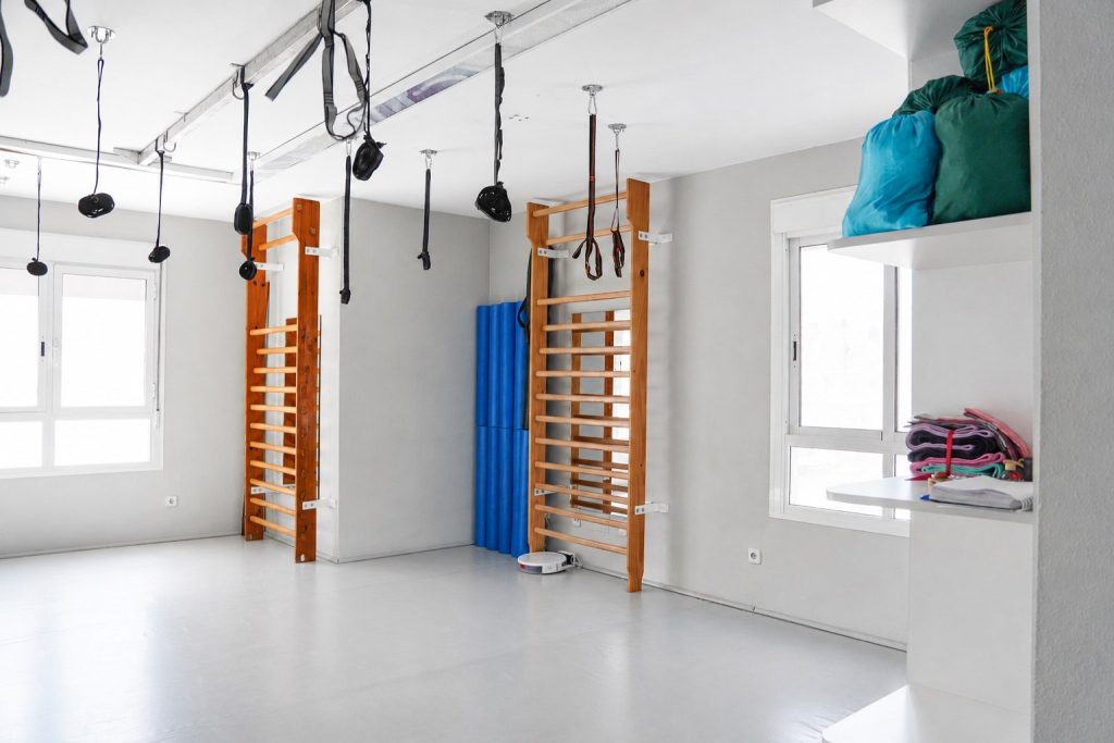 Sala de ejercicio terapéutico con espalderas y arneses de la Clínica Saavedra en Roquetas de Mar
