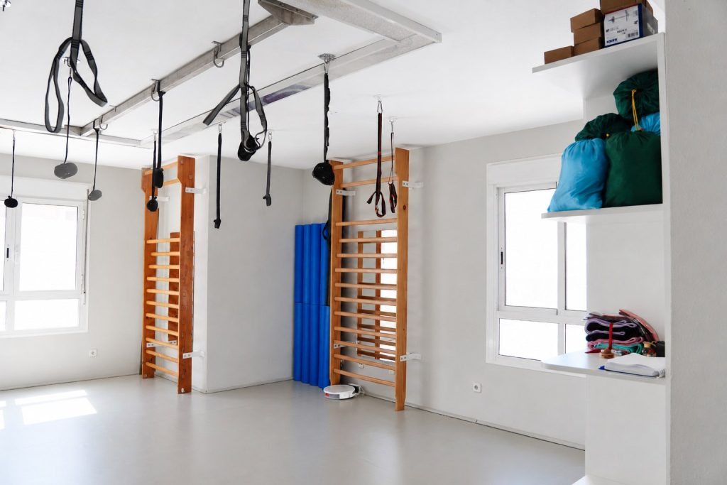 Sala de pilates de la Clínica Saavedra en Roquetas de Mar con espalderas, colchonetas y arneses