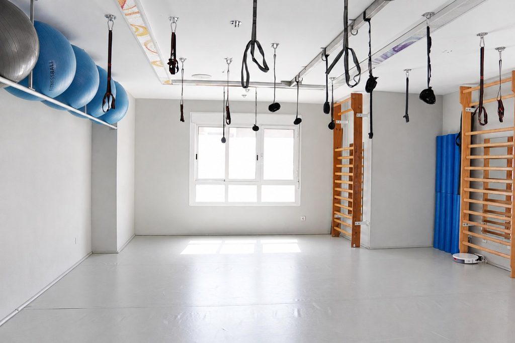 Sala de pilates terapéutico y ejercicio de la Clínica Saavedra en Roquetas de Mar con espalderas y material de suspensión